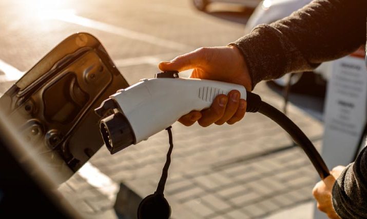 Man's hand plugs EV charger into vehicle