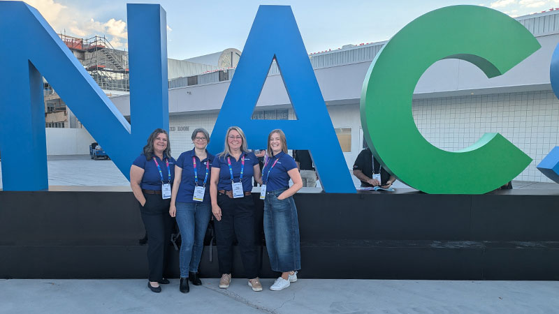 Kalibrate team stood in front on NACS Show sign