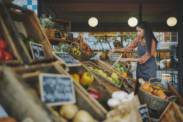Female supermarket owner organizing signs for groceries on display outside her shop